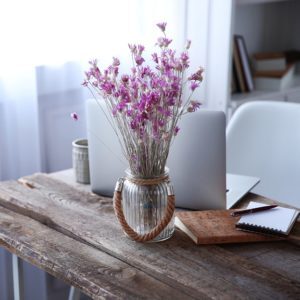 Modern interior. Comfortable workplace. Wooden table with beautiful bouquet of flowers and laptop on it, close up